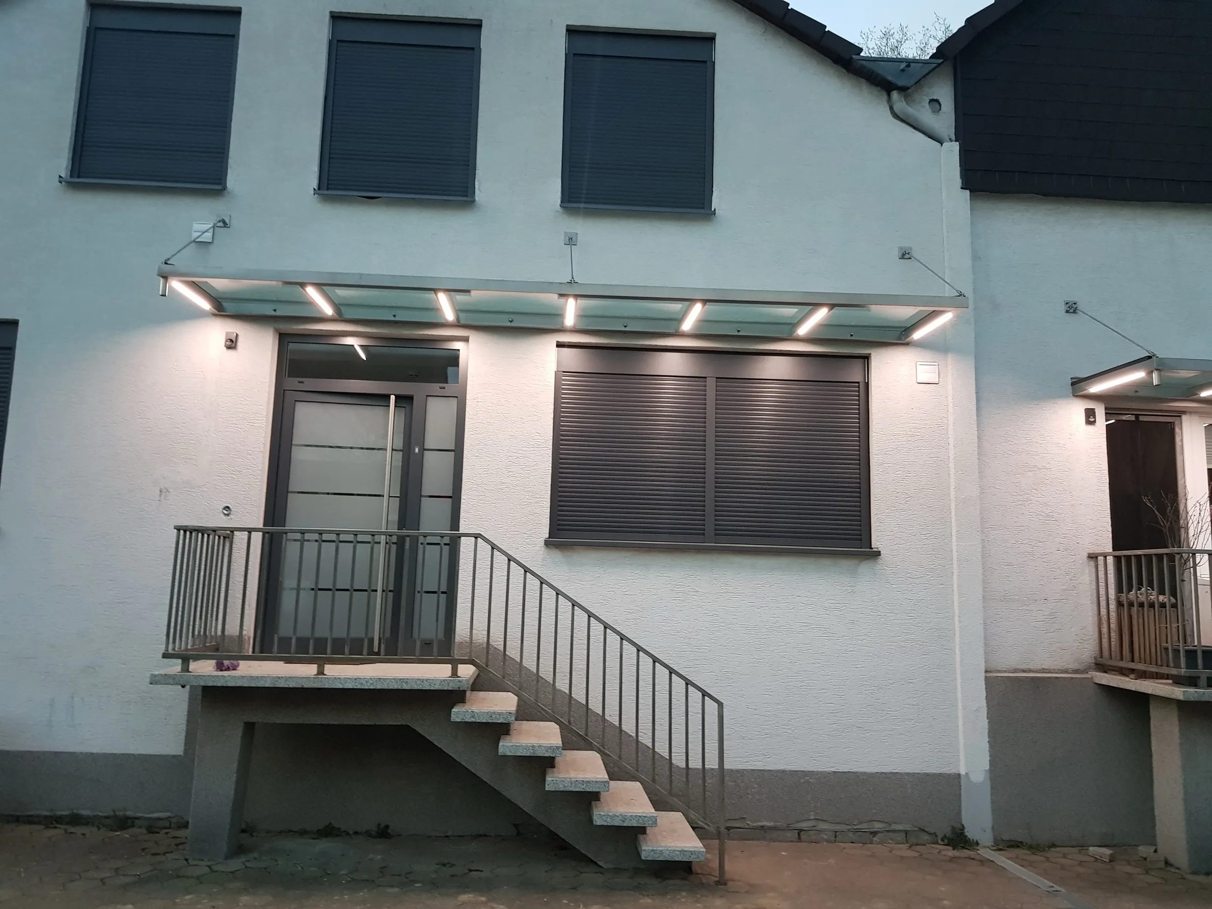 Beleuchtetes Glasvordach über einem Hauseingang